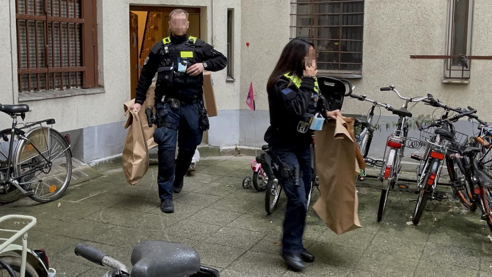 Polizisten tragen Beweismittel in Papiertüten aus dem Haus an der Müllerstraße in Wedding. 