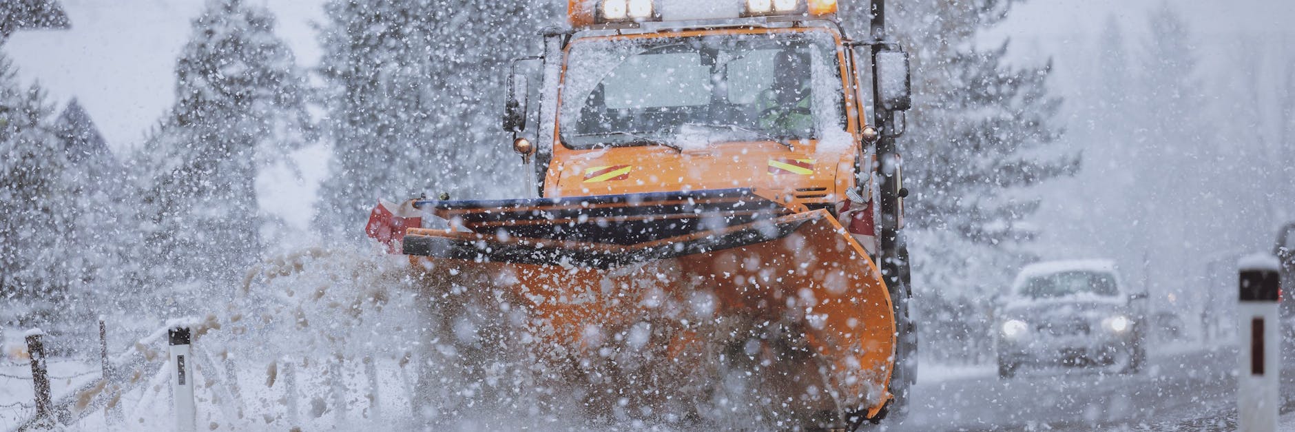 Ein Räumfahrzeug des Winterdienstes räumt eine Straße bei starkem Schneefall.