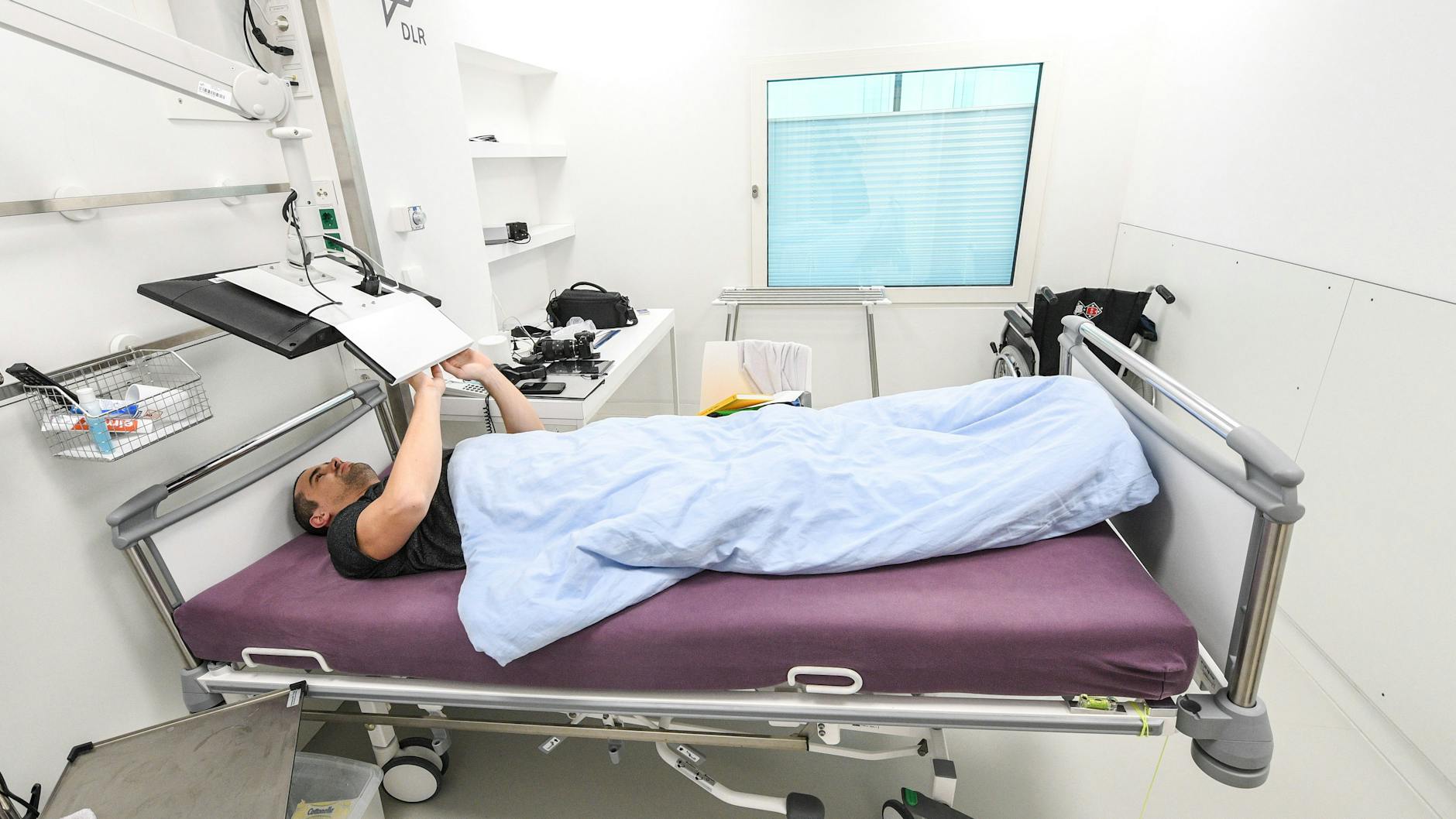 Ein Teilnehmer der Bettruhestudie arbeitet am Computer, während er im Bett liegt. Die Betten sind in der Studie um sechs Grad geneigt, Kopfkissen sind nicht erlaubt. 