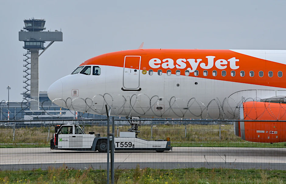 Ein Easyjet-Flugzeug vor der Kulisse des Towers der Deutschen Flugsicherung am BER. Die britische Airline ist die größte Fluggesellschaft am neuen Berliner Hauptstadt-Flughafen.