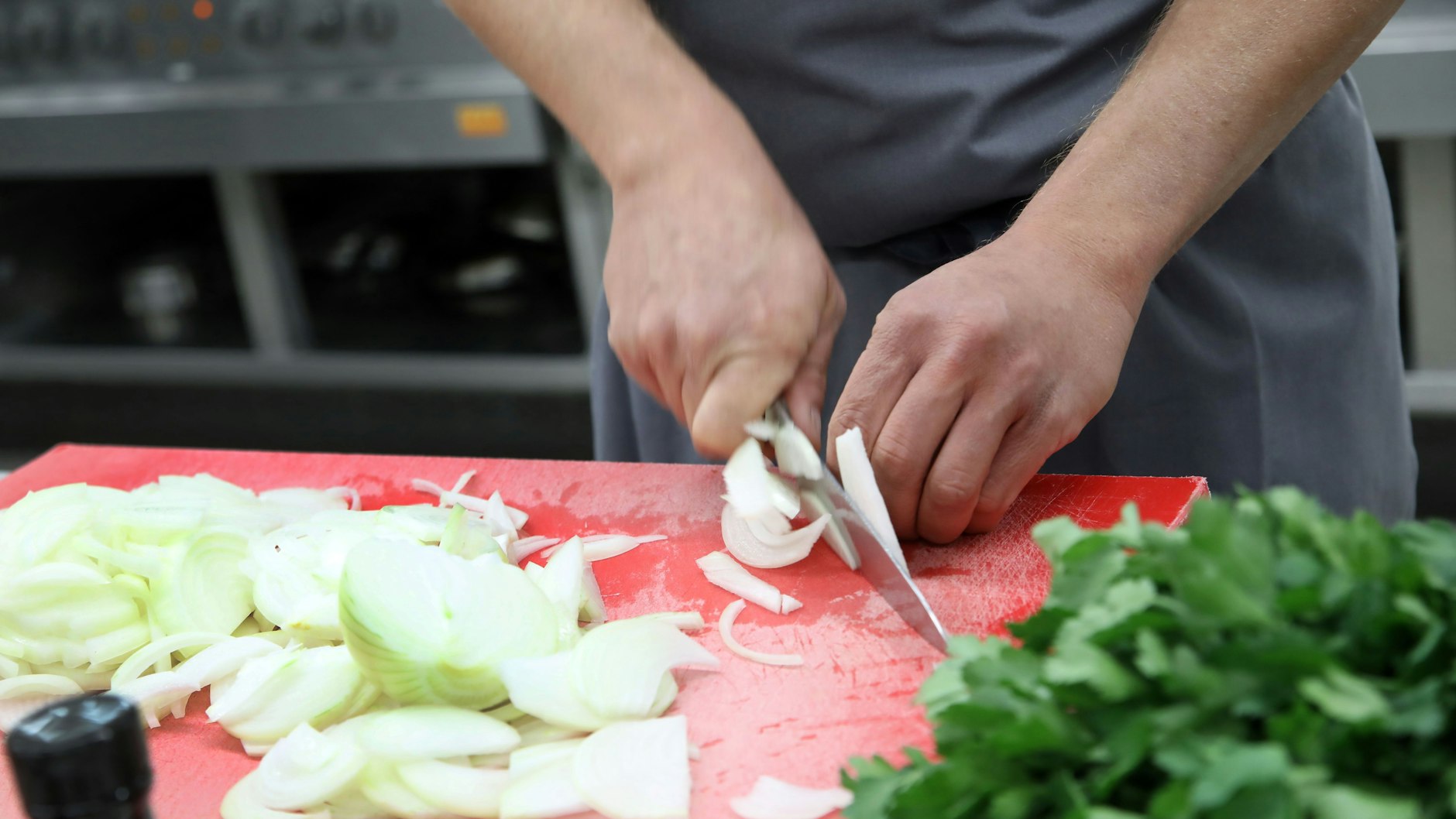 Hier schneidet der Sternekoch die geschälten Zwiebeln für das Schmorzwiebelpüree. Er hat sich sein eigenes Messer mitgebracht.