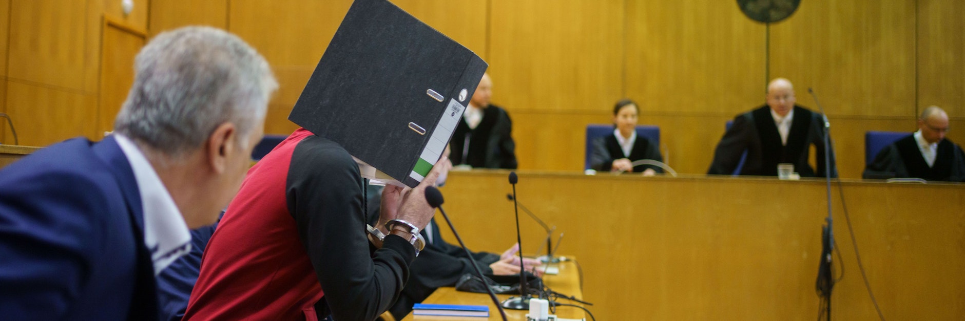 Frankfurt/Main: Mit einem Aktenordner verbirgt der Iraker Taha A.-J. bei der Urteilsverkündung im Frankfurter Oberlandesgericht sein Gesicht.