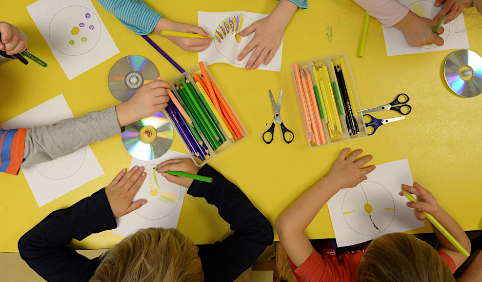 Kinder basteln an einem Tisch in der Kita.