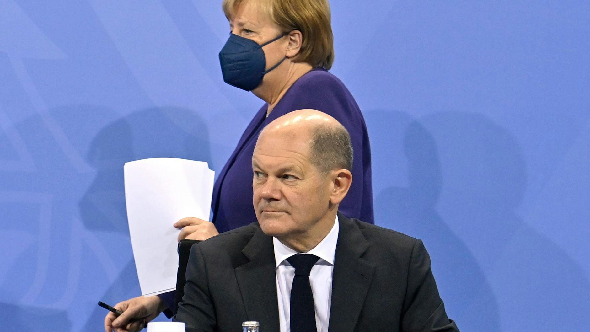 Der designierte Kanzler Olaf Scholz (SPD) äußert sich nach dem Corona-Gipfel vor der Presse. Im Bildhintergrund: die geschäftsführende Kanzlerin Angela Merkel (CDU). 