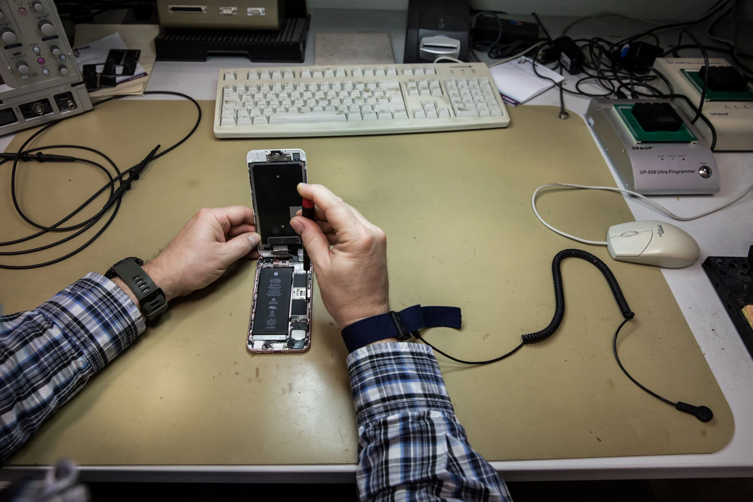 Ein Armband, das mit einem Druckknopf an der Tischmatte befestigt ist, verhindert, dass durch elektrostatische Aufladung die empfindlichen Chips des geöffneten Handys beschädigt werden.