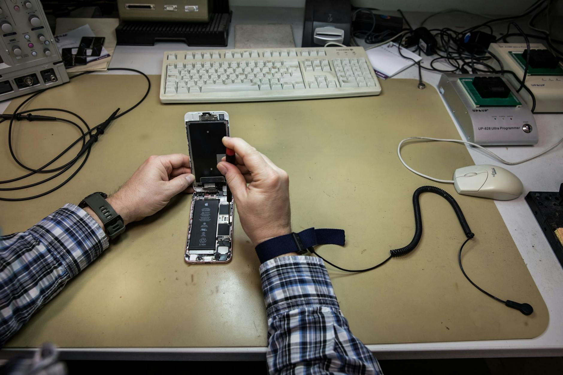 Ein Armband, das mit einem Druckknopf an der Tischmatte befestigt ist, verhindert, dass durch elektrostatische Aufladung die empfindlichen Chips des geöffneten Handys beschädigt werden.