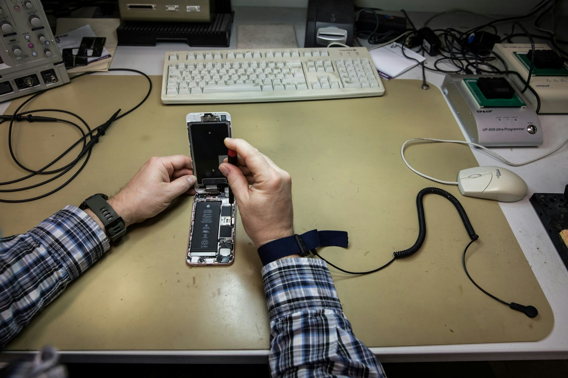 Ein Armband, das mit einem Druckknopf an der Tischmatte befestigt ist, verhindert, dass durch elektrostatische Aufladung die empfindlichen Chips des geöffneten Handys beschädigt werden.