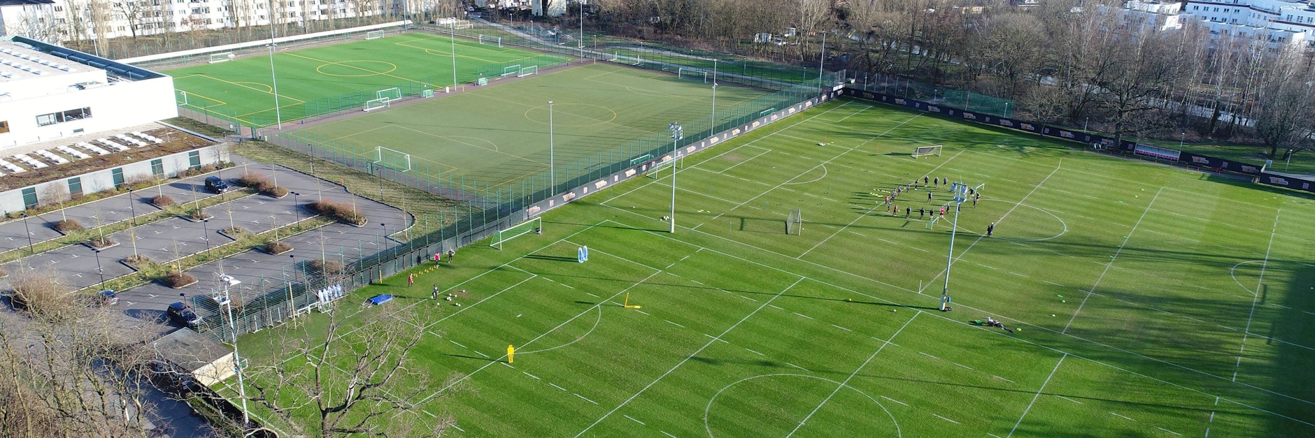 Blick auf die Ballsporthalle Hämmerlingstraße mit den beiden Kunstrasenplätzen davor und dem bisherigen Trainingsgelände der Eisernen. 