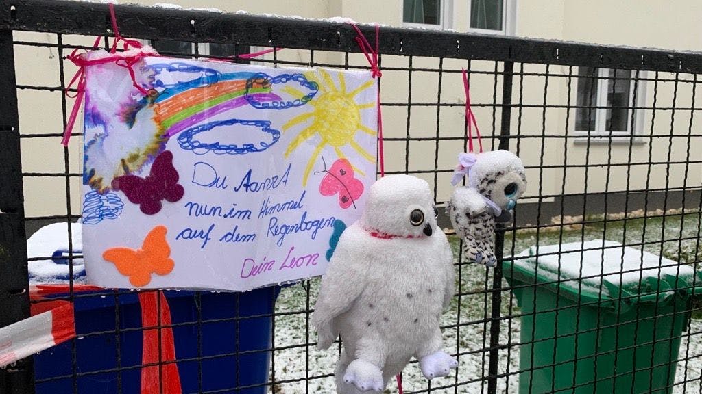 Ein Schuljunge hat einen letzten Gruß für eines der toten Mädchen gemalt und geschrieben. Daneben hängen zwei Plüsch-Eulen.