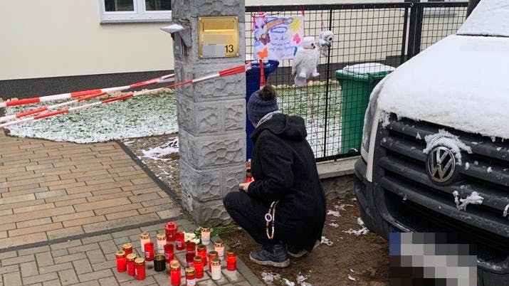 Eine Frau stellt eine Kerze am Tor zum Todeshaus auf.