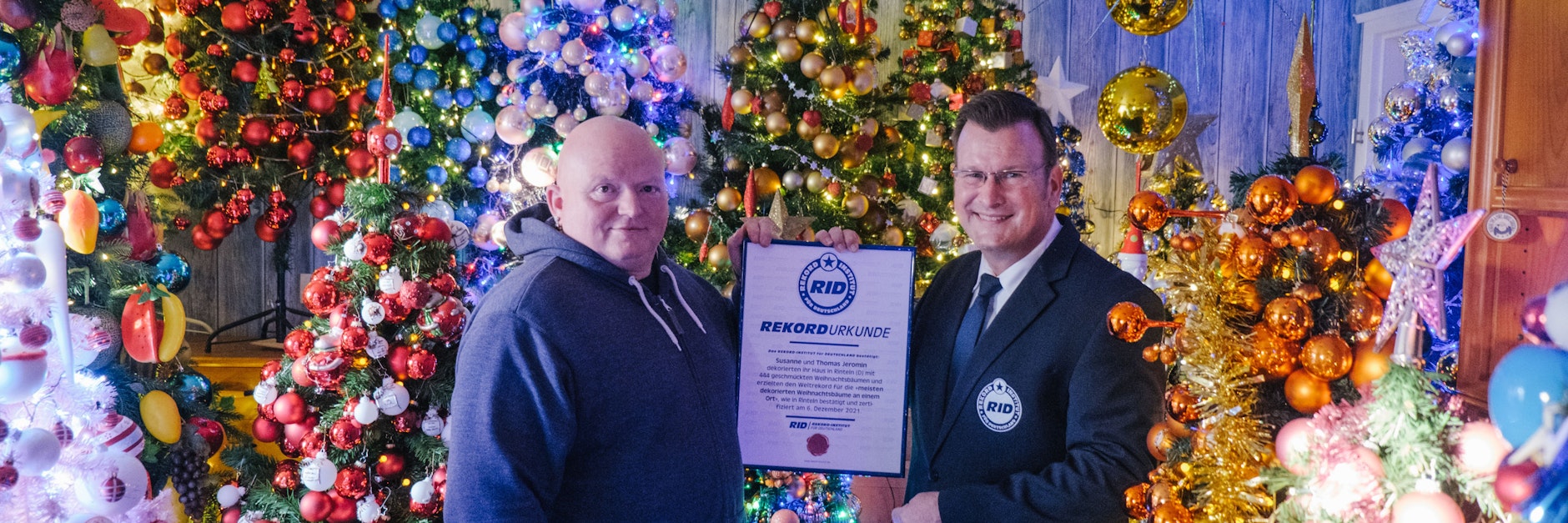 Man sieht die Wohnung vor Bäumen nicht. Olaf Kuchenbecker (r.), RID-Rekordrichter, überreicht die Rekordurkunde an Thomas Jeromin.