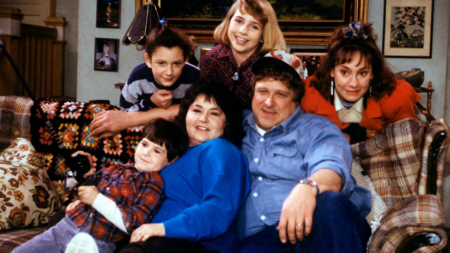 Die Schauspieler der US-Sitcom „Roseanne“, Michael Fishman (als DJ Conner, vorne, v. l. n. r.), Roseanne Barr (als Roseanne), John Goodman (als Dan Conner) und Sara Gilbert (als Darlene Conner, hinten, v. l. n. r.), Alicia Goranson (als Becky Conner) und Laurie Metcalf (als Jackie Harris) – Aufnahme aus dem Jahr 1989.