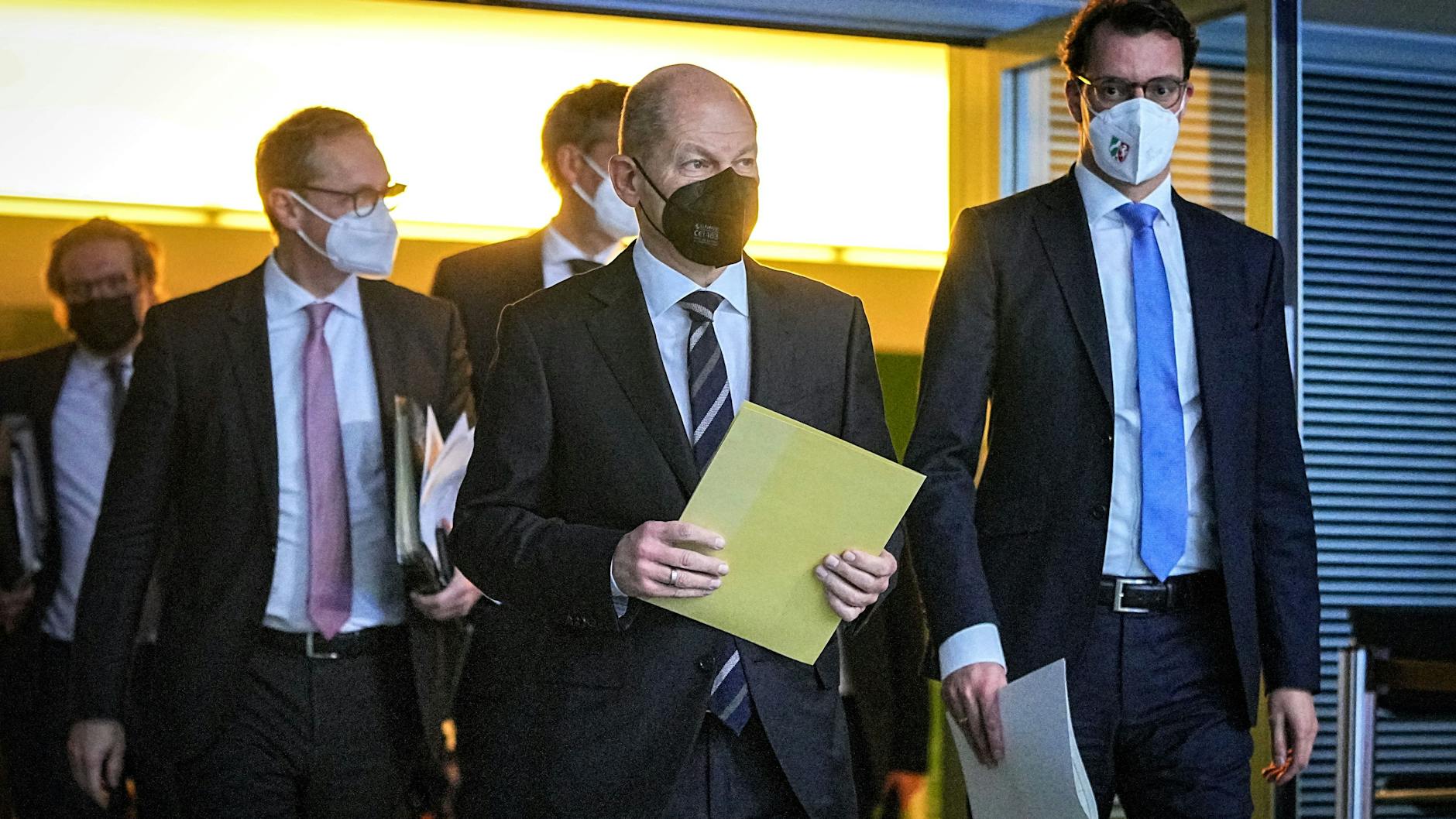 Bundeskanzler Olaf Scholz (M., SPD) kommt neben Hendrik Wüst (r., CDU), Ministerpräsident von Nordrhein-Westfalen, und Michael Müller (l., SPD), Regierender Bürgermeister von Berlin, zu einer Pressekonferenz nach den Beratungen der Bundesregierung mit den Ministerpräsidentinnen und Ministerpräsidenten der Länder. 