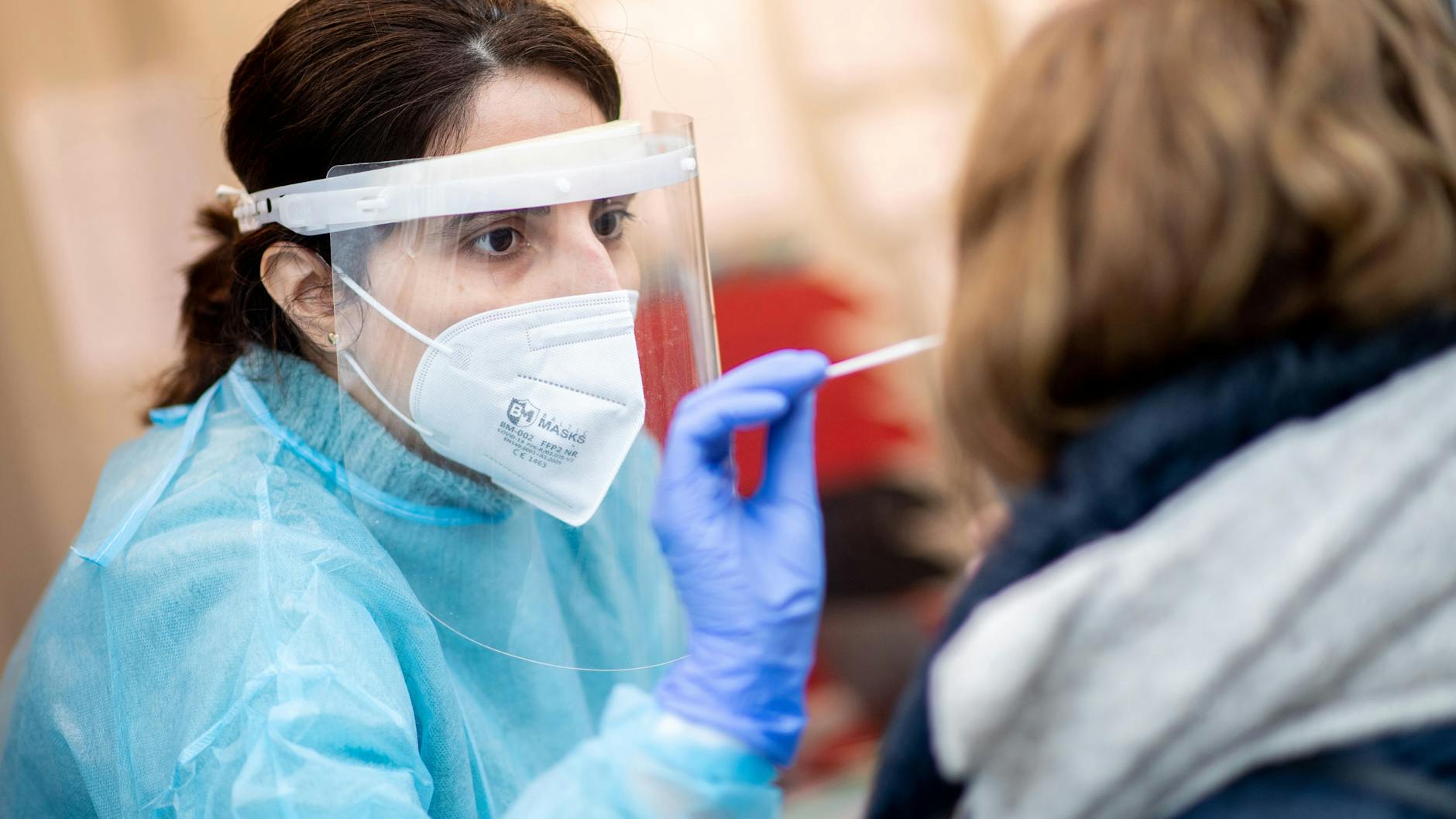 Eine Mitarbeiterin einer Teststation nimmt einen Abstrich von einer Frau. In Brandenburg geraten die Gesundheitsämter aufgrund der vielen positiven Tests an ihre Belastungsgrenzen.