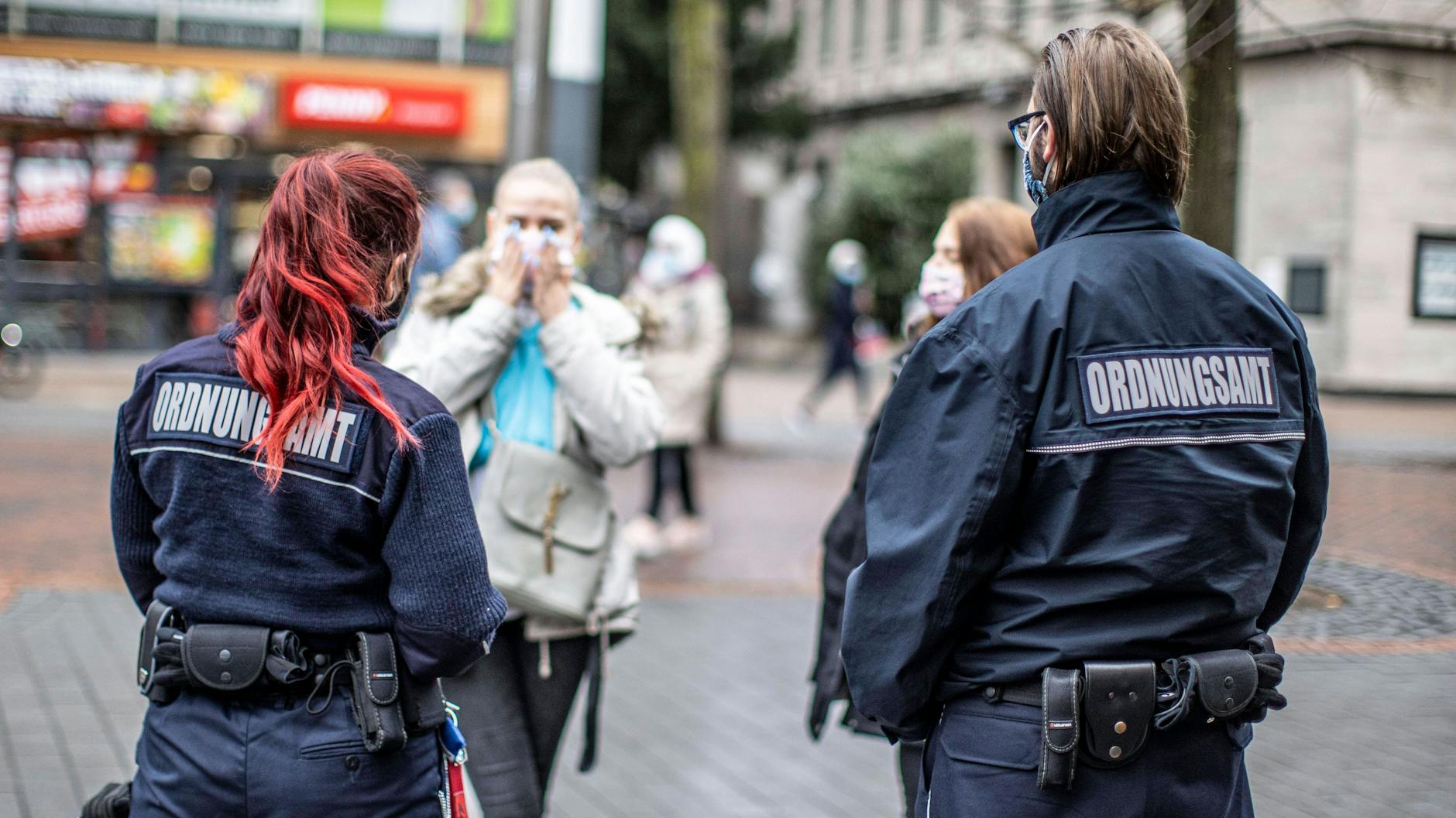 Mitarbeiter eines Ordnungsamte bei einer Kontrolle von Passanten (Symbol).