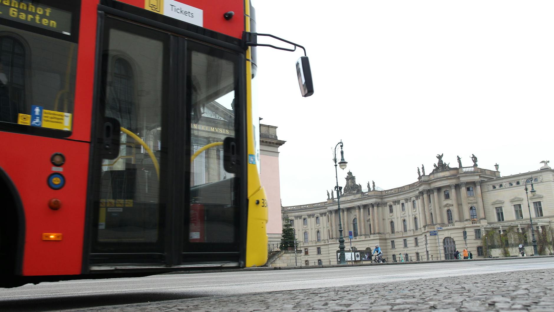 Doppelstöckig durch Berlins gute Stube. Ein BVG-Doppeldecker fährt am Bebelplatz die Linden entlang. Im Hintergrund: die Alte Bibliothek und ein kleines rosarotes Stück der Staatsoper.