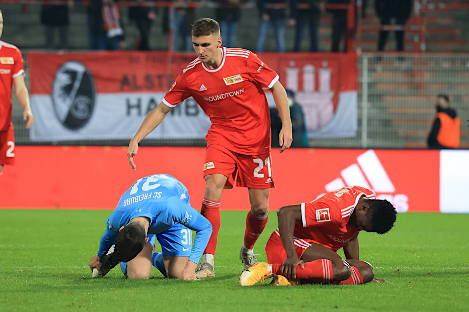 Wiedersehen macht Schmerzen: Unions Taiwo Awoniyi (r.) und der ehemalige Unioner Keven Schlotterbeck (l.) haben etwas abbekommen. Grischa Prömel (M.) eilt zu Hilfe.