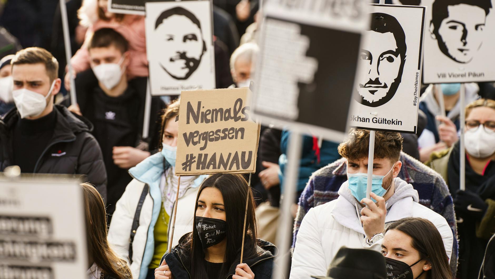 Bei einer Kundgebung zum Gedenken an die Anschlagsopfer von Hanau trägt eine Frau ein Plakat mit der Aufschrift „Niemals vergessen #Hanau“. 