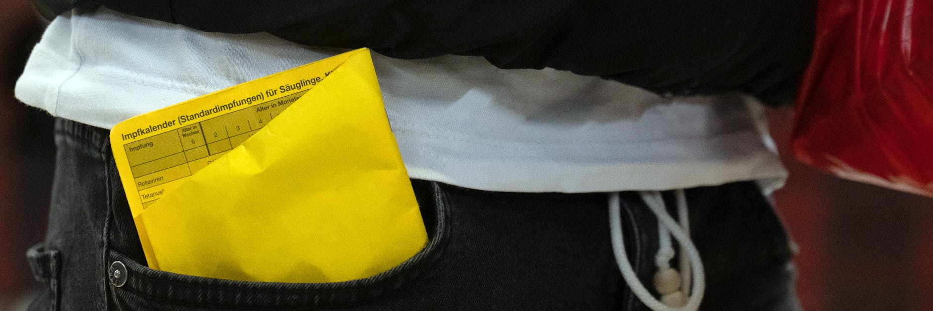 Ein Impfpass steckt zerknüllt in der Hosentasche.