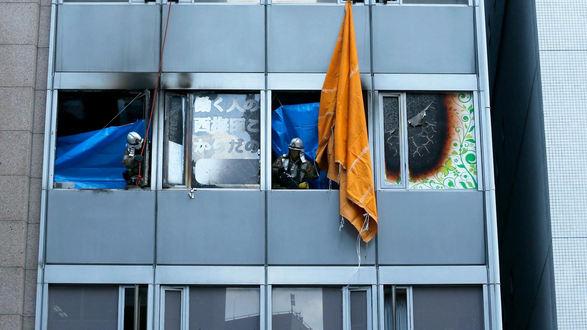 Feuerwehrleute stehen in einem Gebäude. Bei einem Hochhausbrand in Japan sind vermutlich mehr als zwei Dutzend Menschen ums Leben gekommen.