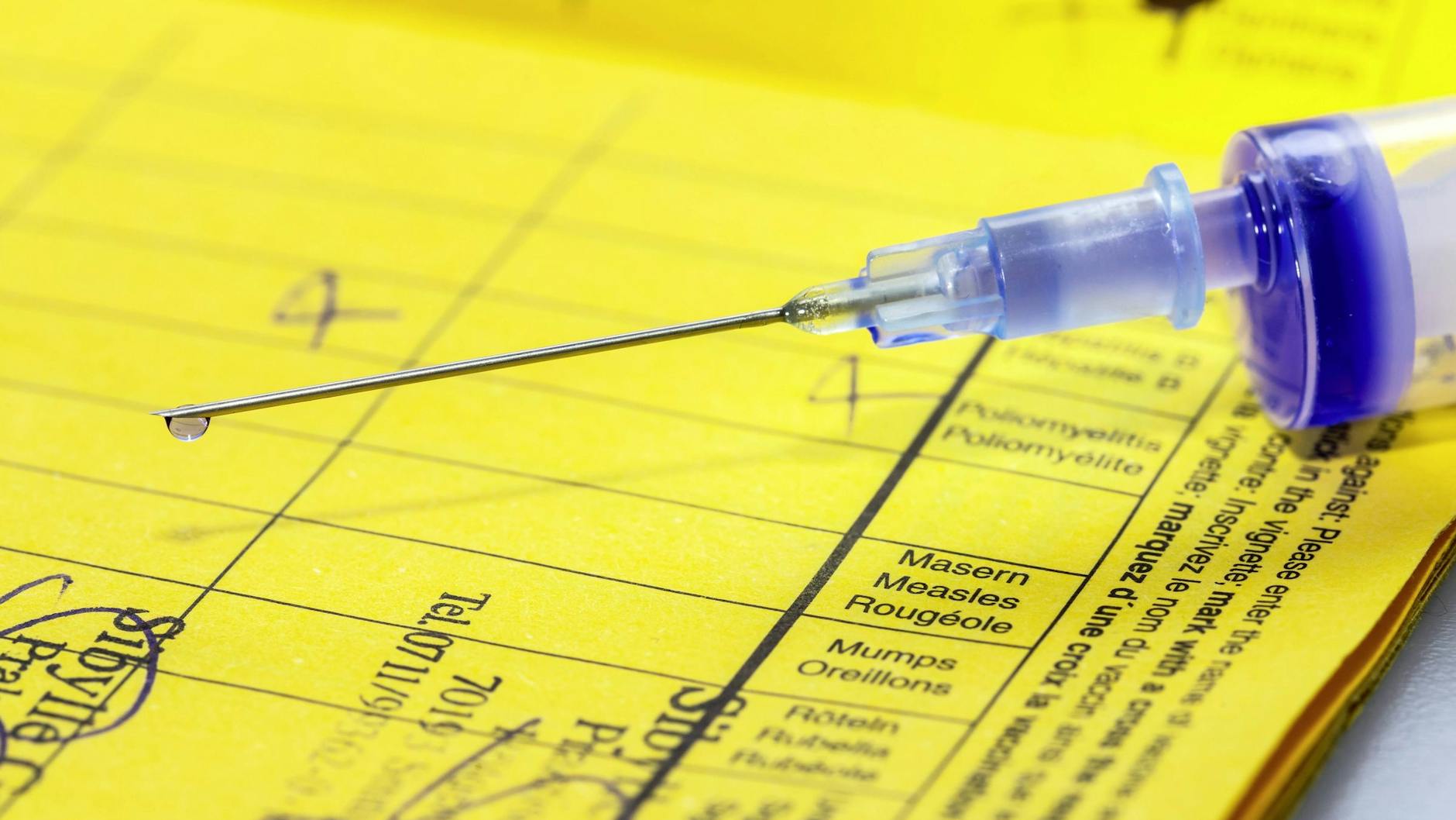 Eine Spritze liegt auf einem Impfpass.