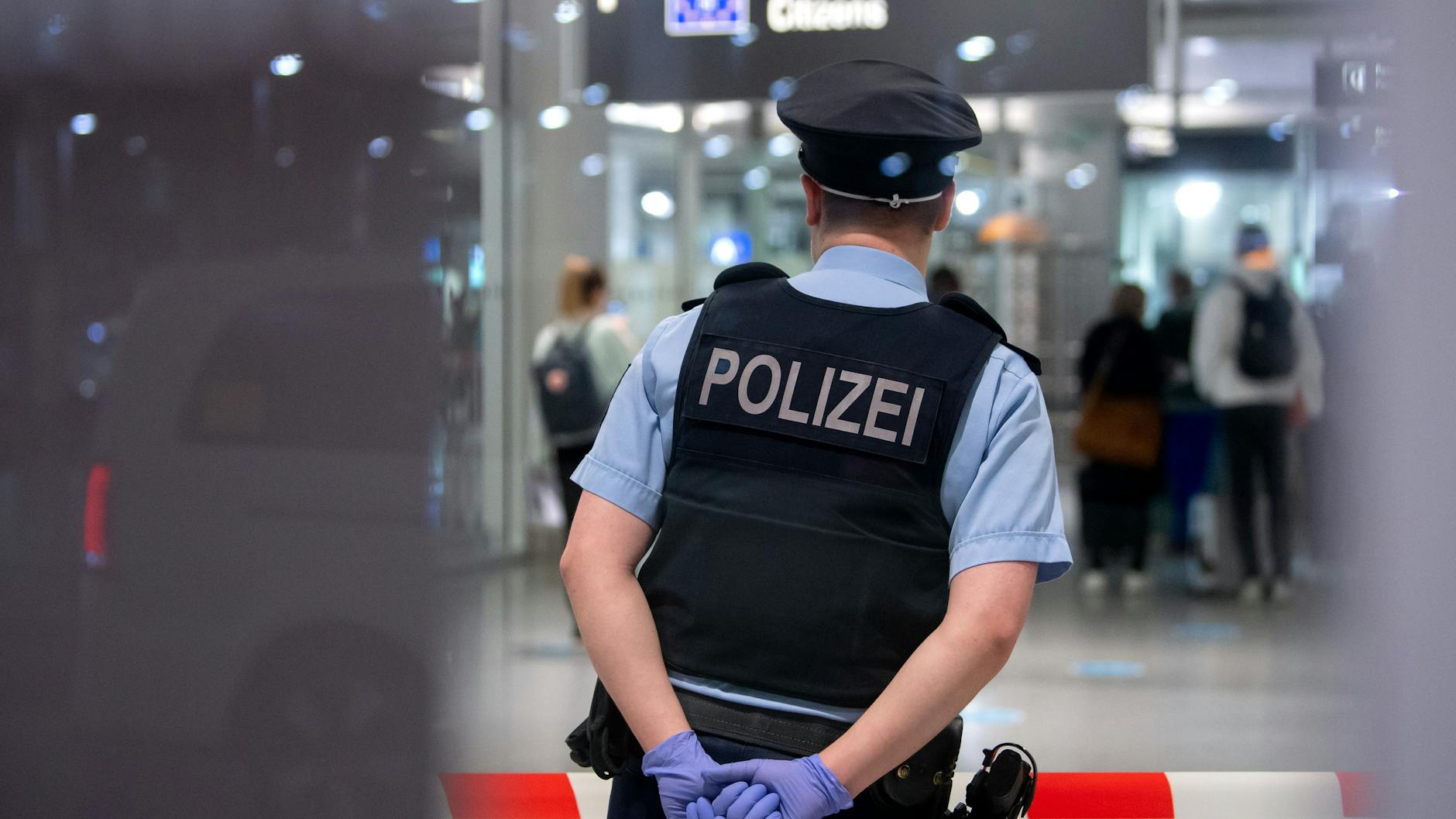 Ein Polizist steht bereit, um Einreisende am Flughafen München zu kontrollieren (Archivbild).