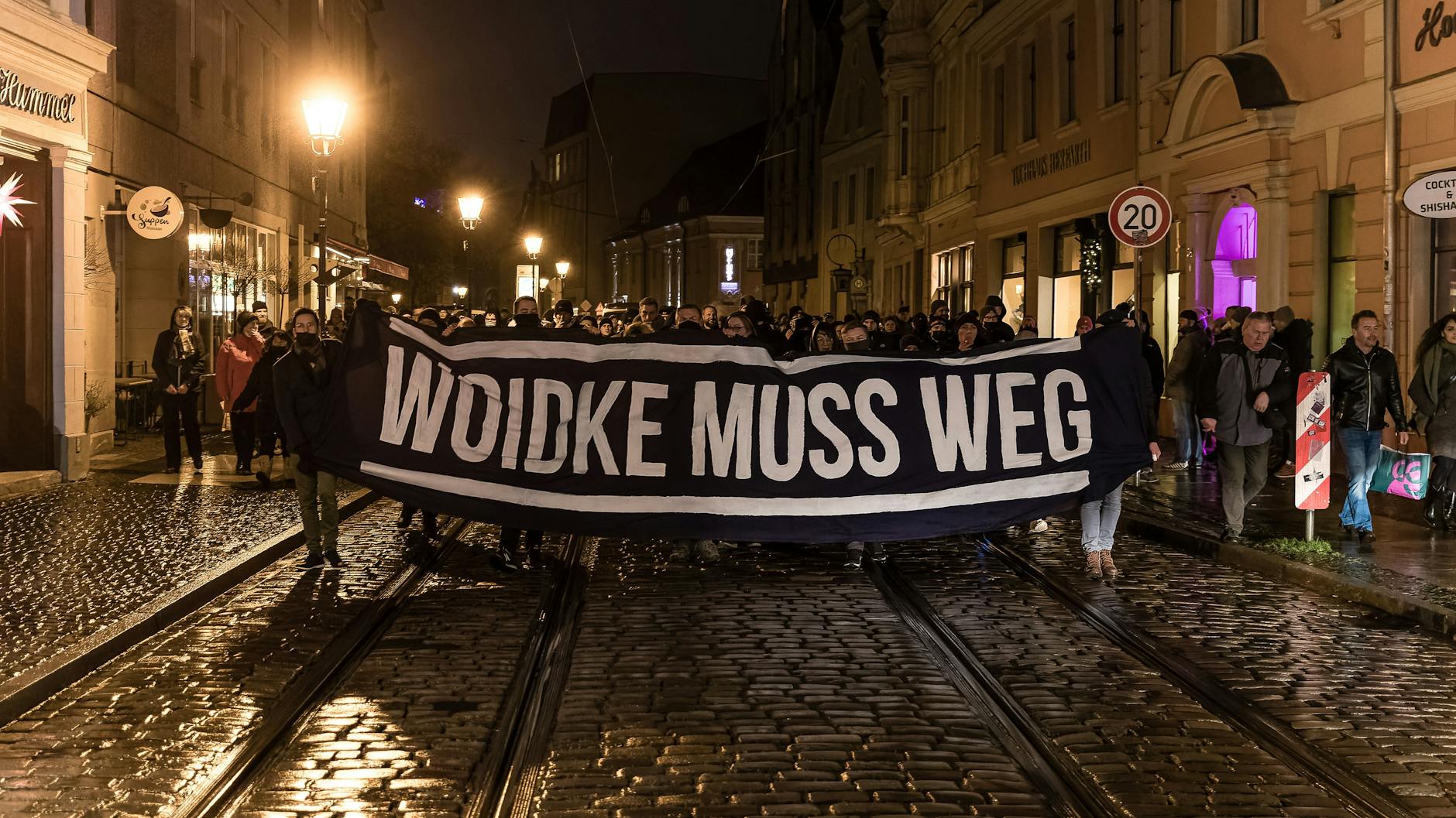 Mit einem Schild mit der Aufschrift „Woidke muss weg“ marschieren Demonstranten entlang des Cottbuser Altmarktes.