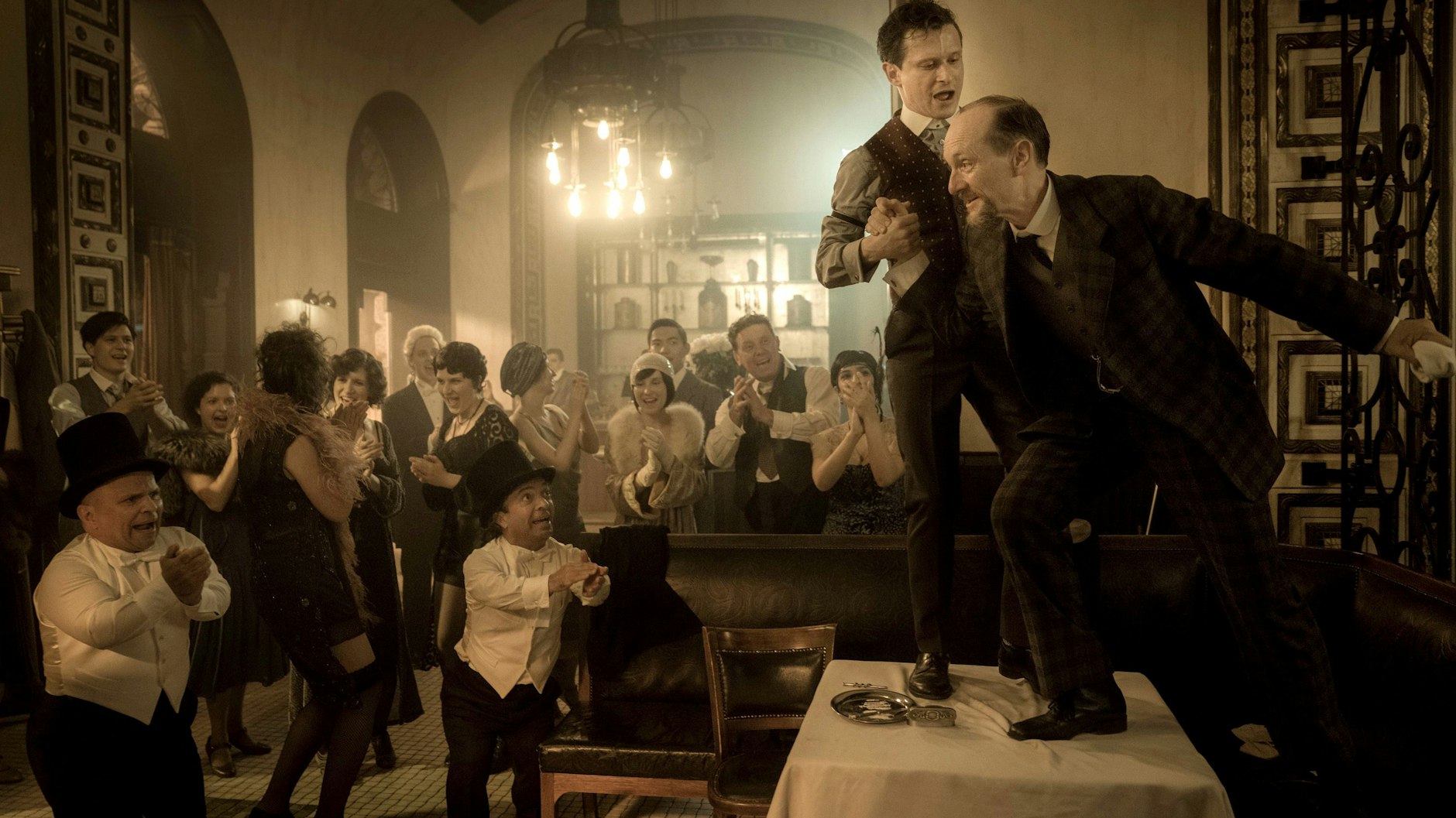 KaDeWe-Juniorchef Harry (Joel Basman, oben, l.) feiert ausgelassen mit dem Geschäftsmann Furstenberger (Michael Ihnow) in einer Szene aus Folge 3.