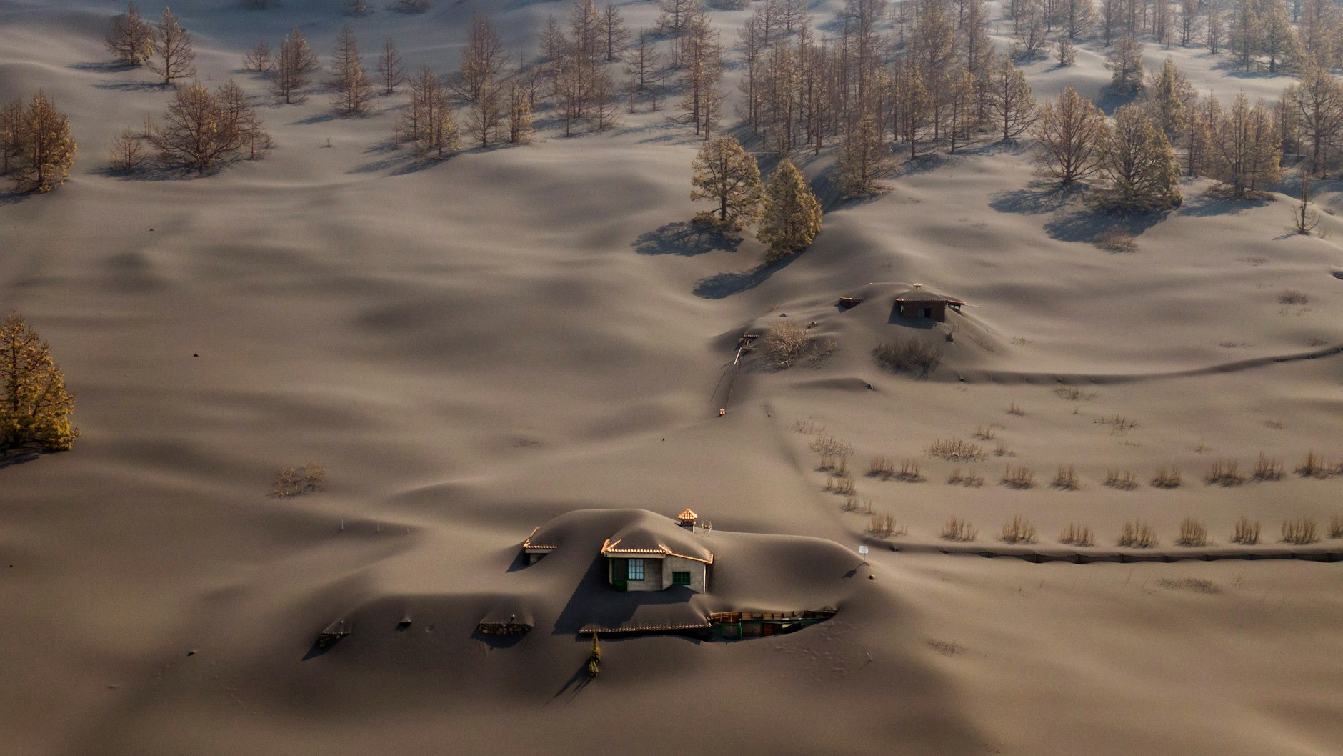 Teile der Insel wirken wie eine Mondlandschaft oder wie von braunem Schnee überzogen. Aus der Asche ragen hier und da nur Dächer verschütteter Häuser heraus.
