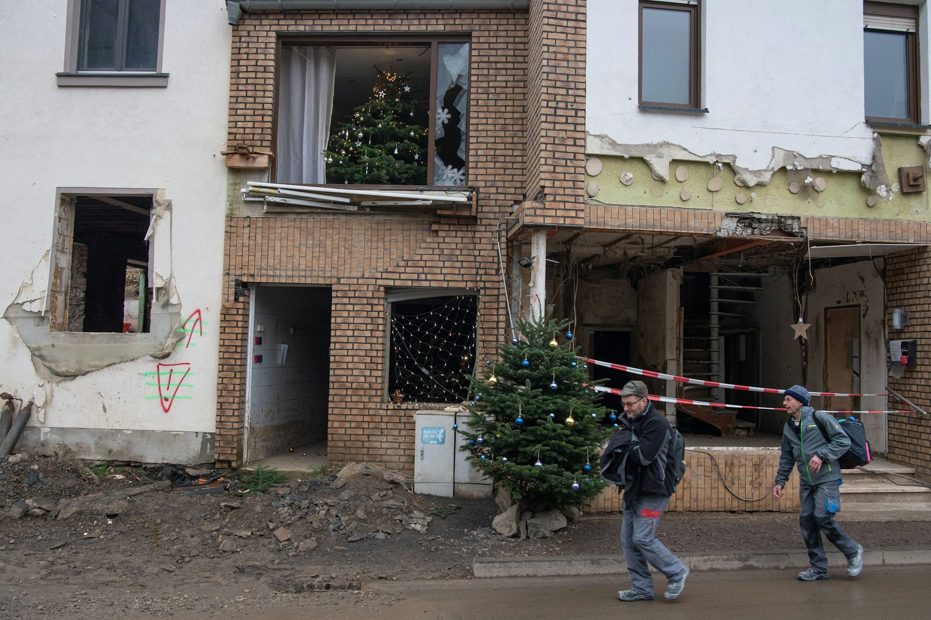Weihnachtsbäume stehen in dem Winzerort Mayschoß in Fenstern von Gebäuden, die bei der Flutkatastrophe im Juli zerstört wurden.