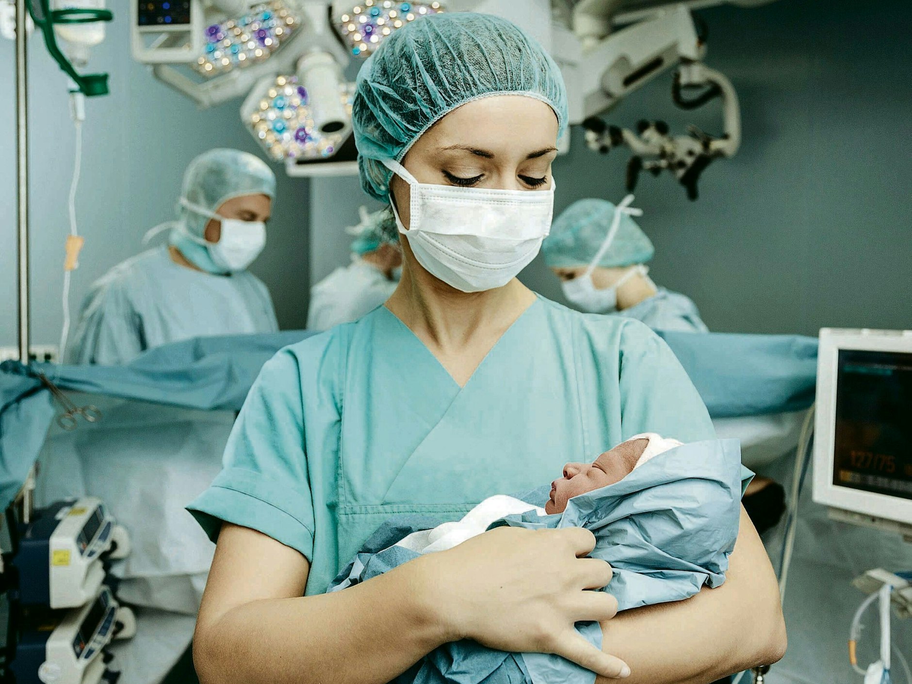 Eine Hebamme hält im Kreißsaal ein Neugeborenes im Arm.