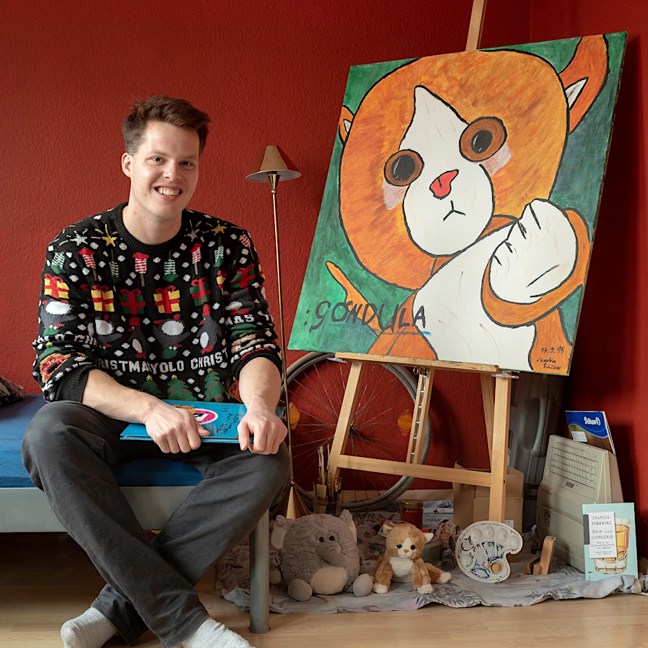 Martin Schüler mit einem seiner Gemälde von Gondula, der Plüschkatze.