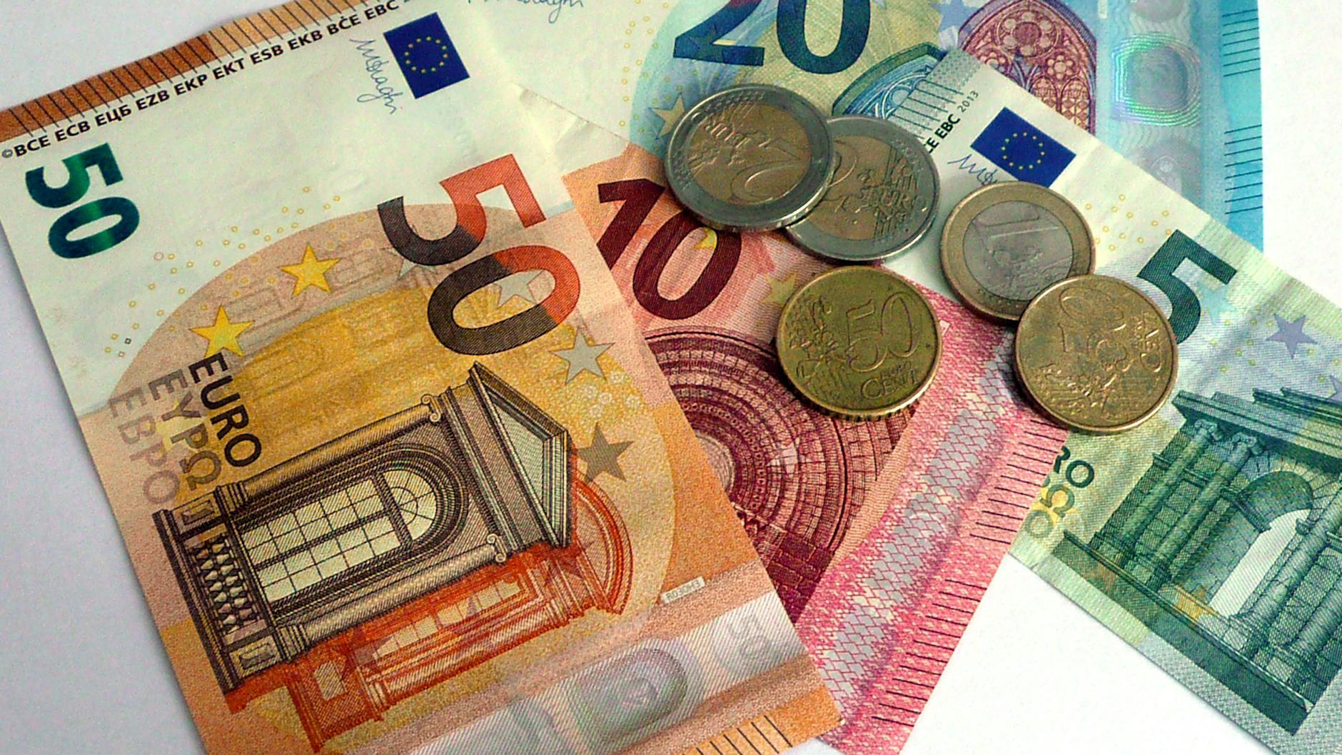 Euro Banknoten und Euro Muenzen liegen auf einem Tisch. (Symbolbild).