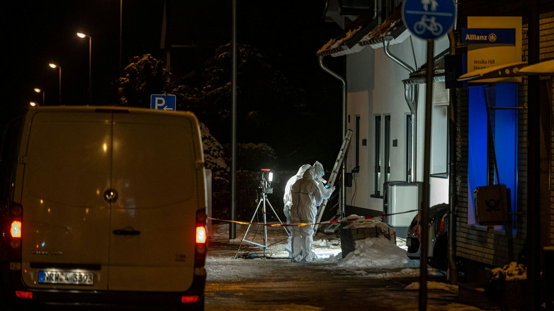 Beamte der Spurensicherung stehen nach einem Brand vor einem Wohnhaus.