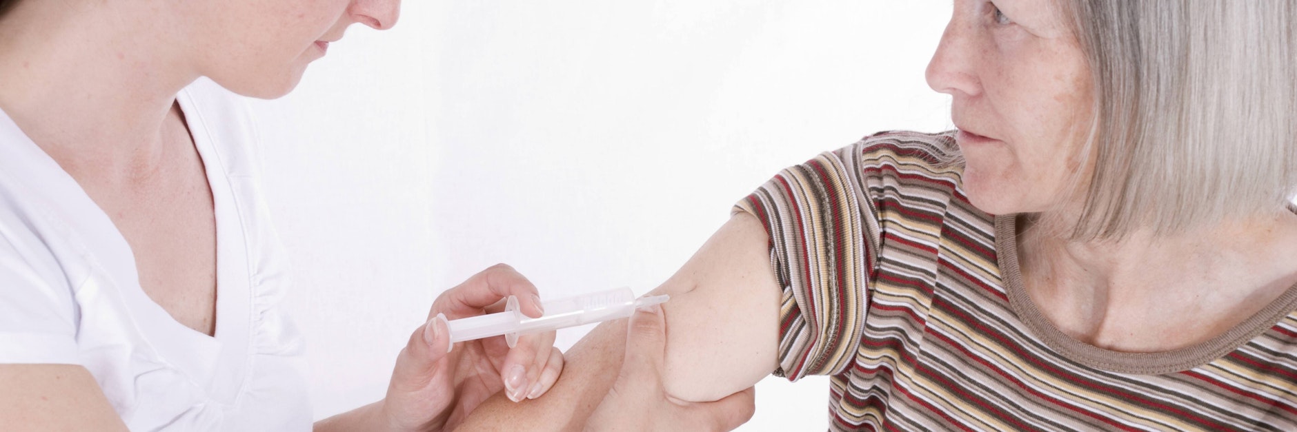 Eine Ärztin gibt einer älteren Frau eine Spritze in den Oberarm.&nbsp;