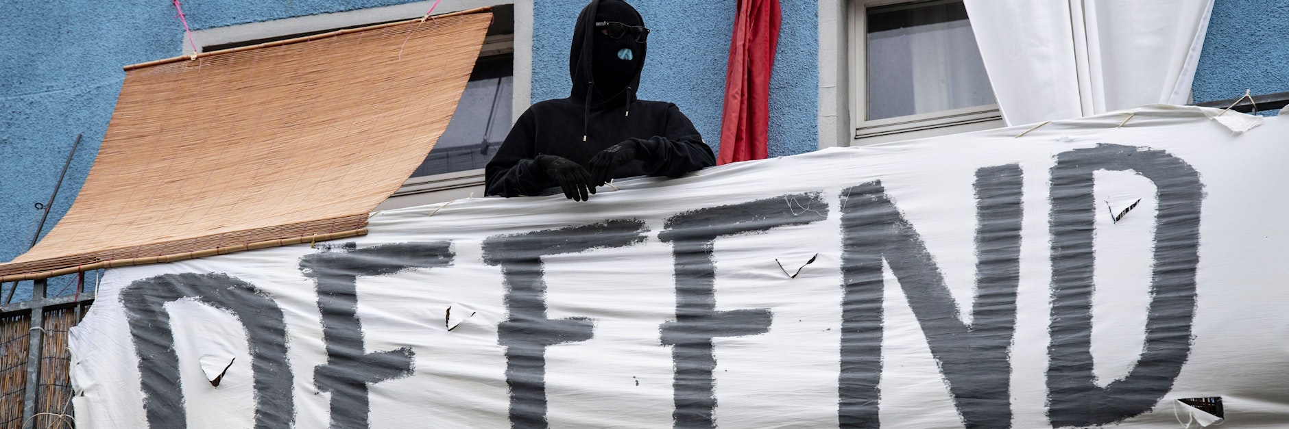 Ein vermummter Mann steht bei einem früheren Einsatz der Polizei Berlin auf einem Balkon eines Hauses in der Rigaer Straße.