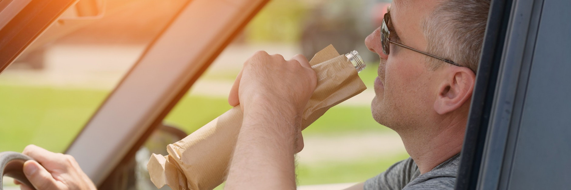 Ein Mann trinkt Alkohol am Steuer (Symbolbild).