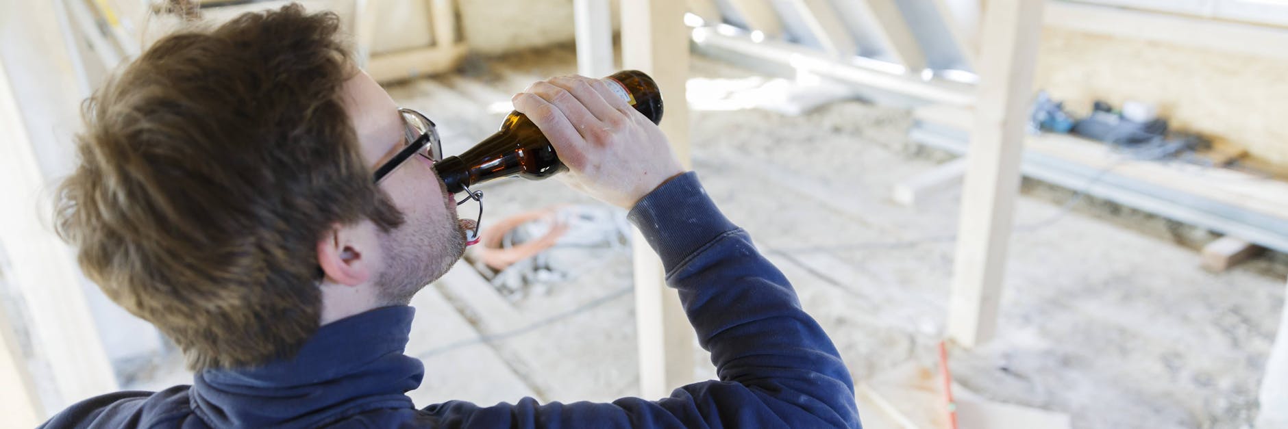Ein Mann trinkt auf einer Baustelle ein Bier (Symbolbild).