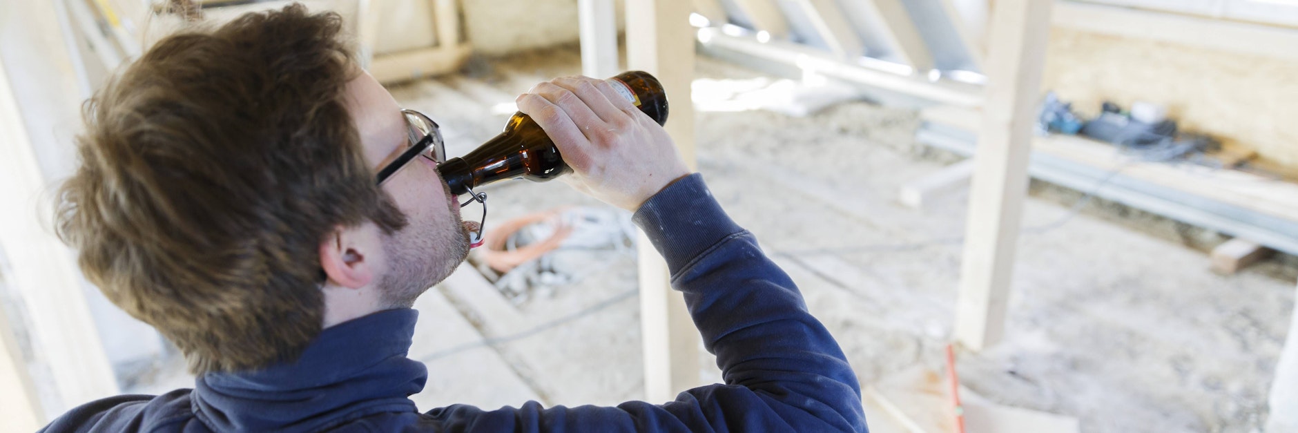 Ein Mann trinkt auf einer Baustelle ein Bier (Symbolbild).