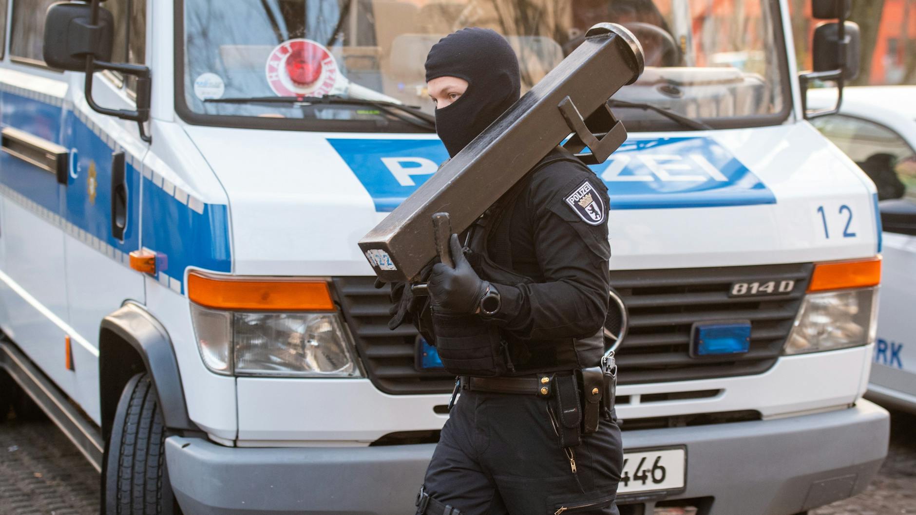 Ein Beamter eines mobilen Einsatzkommandos (MEK) trägt eine Ramme zu einer Wohnung. 