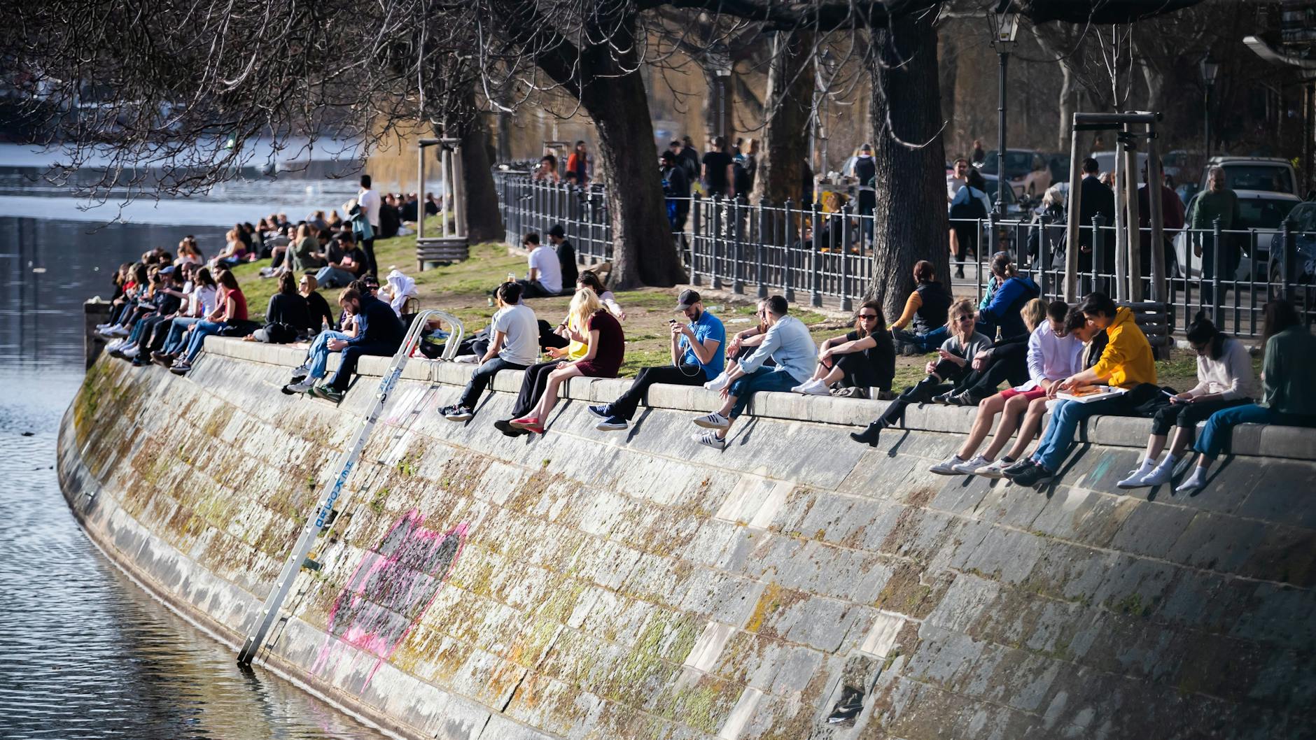 Sonnenhungrige sitzen am Ufer des Landwehrkanals in Kreuzberg.