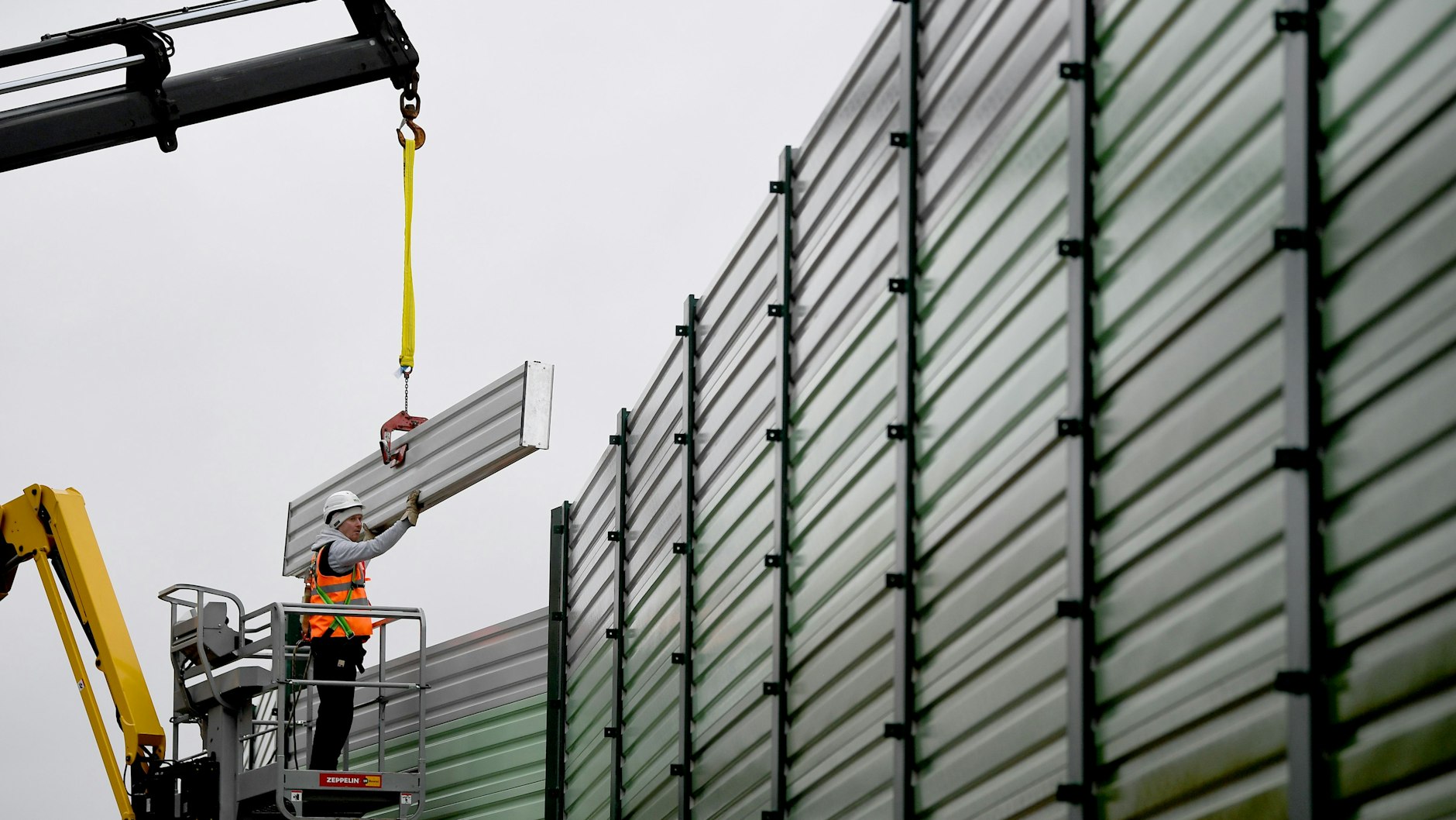 Bauarbeiter errichten einen Lärmschutz an der Baustelle zum Wiederaufbau der Dresdner Bahn am Bahnübergang Wolziger Zeile. 