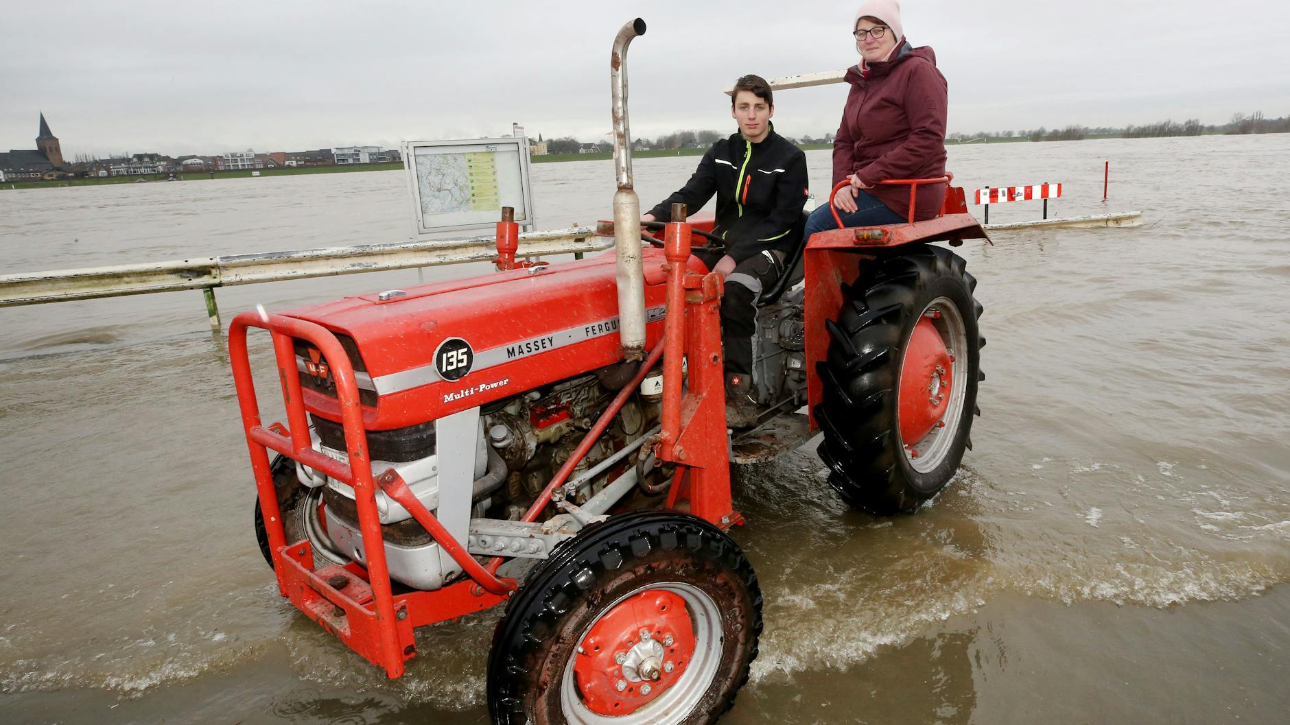 Sandra van Schöll (r) und ihr Sohn Simon schauen sich mit ihrem Trecker das Rheinhochwasser in Grietherort an. 