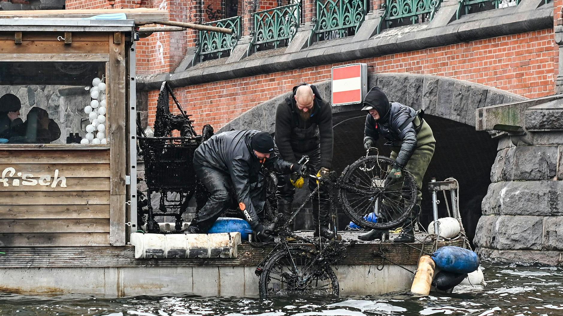 Gemeinsam ziehen die Männer ein Fahrrad nach dem anderen aus der Spree.<br>