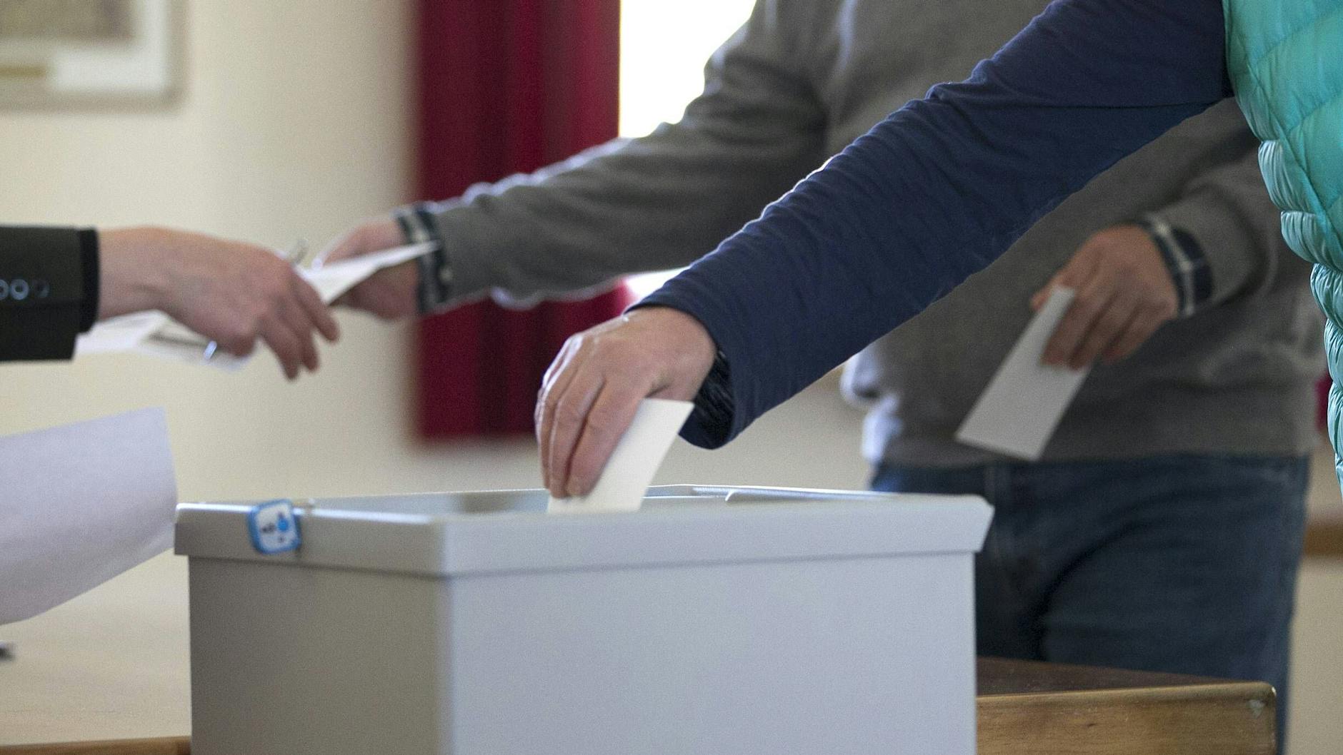 Ein Wähler steckt im Wahlbüro einen Wahlumschlag in eine Wahlurne (Symbolbild)