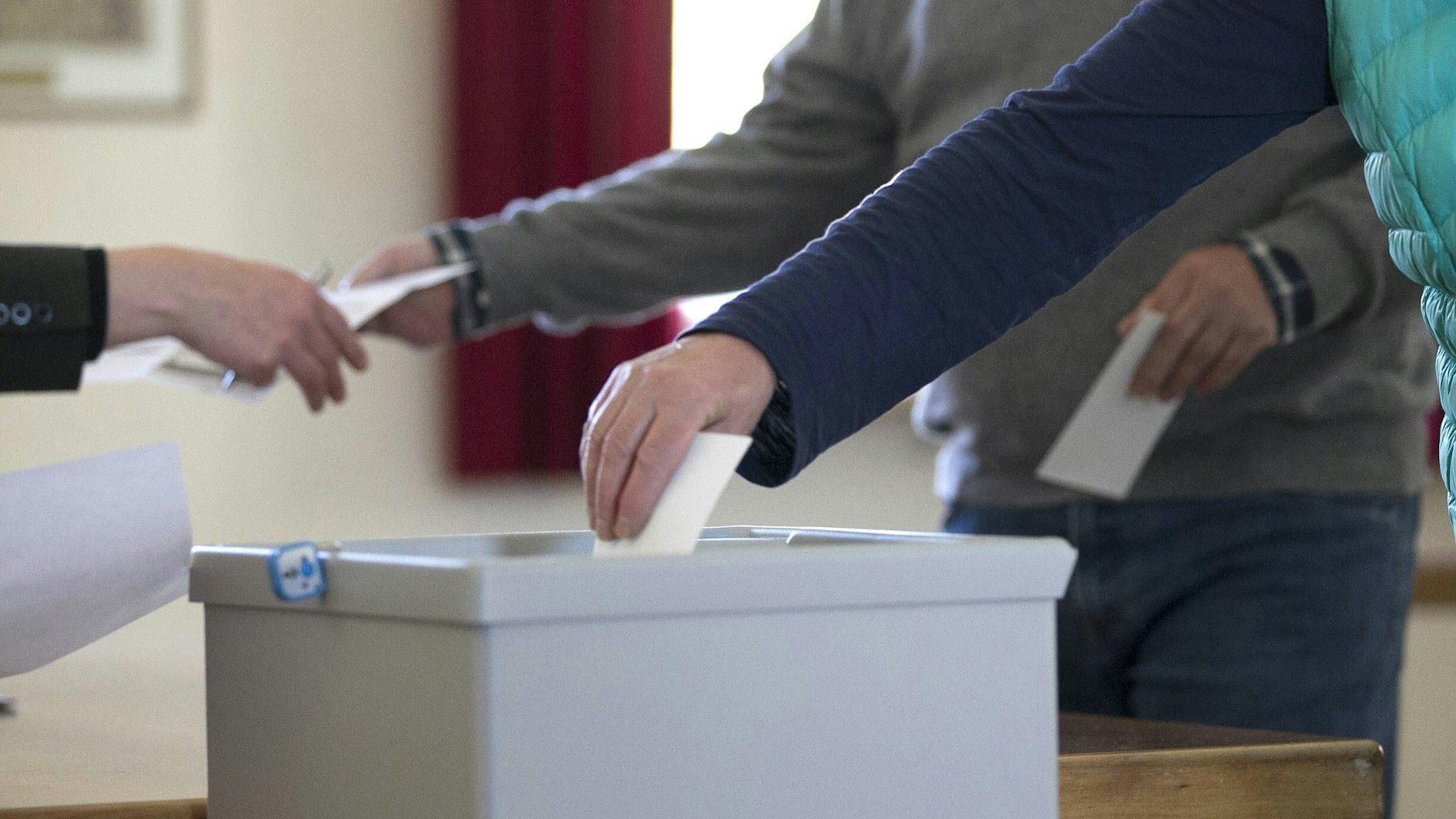 Ein Wähler steckt im Wahlbüro einen Wahlumschlag in eine Wahlurne (Symbolbild)