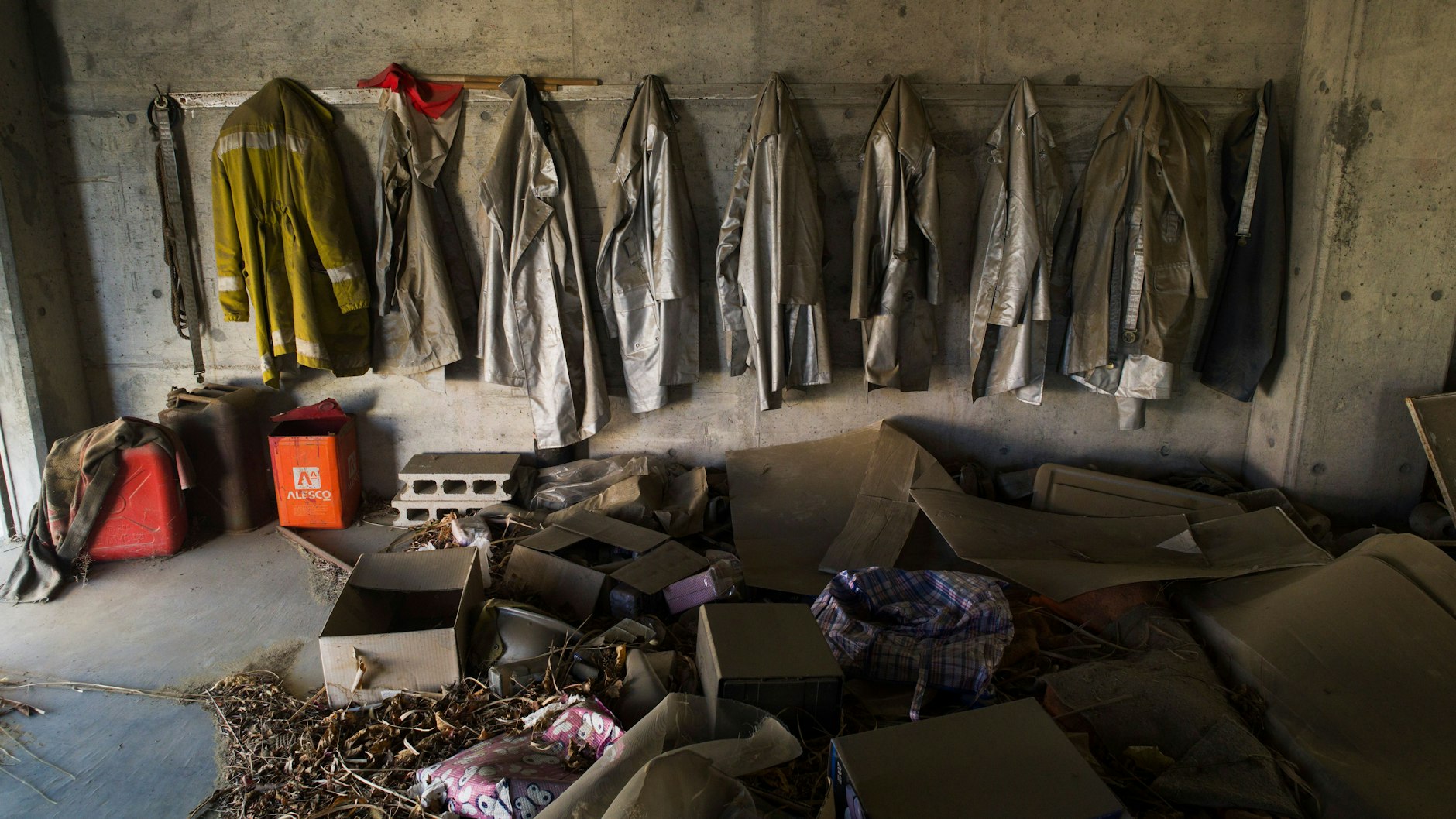 Im Raum einer verlassenen Feuerwache hängen Uniformen.