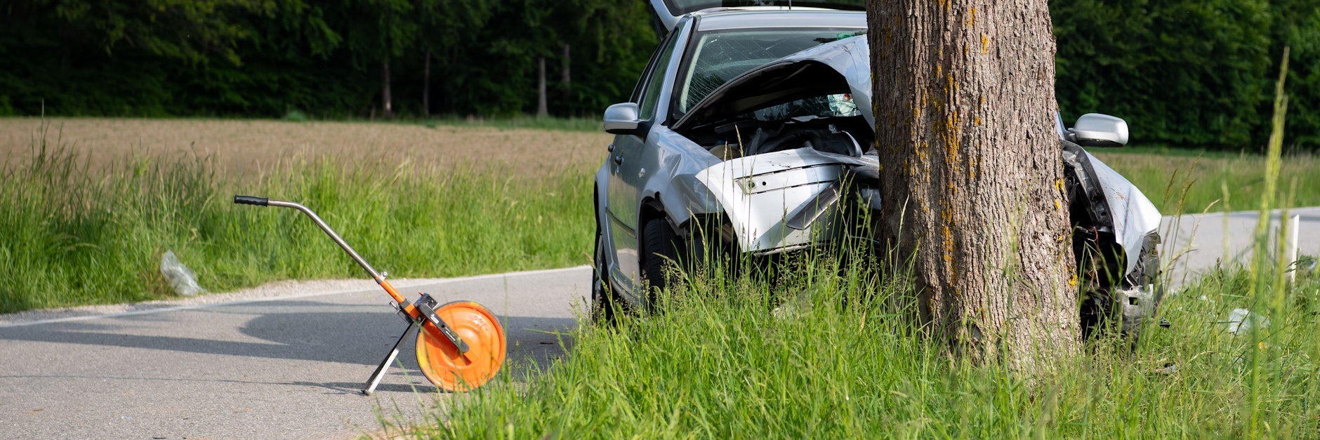 Ein zerstörtes Auto steht an der Unfallstelle. Ein Autofahrer ist in Pöcking bei Starnberg in eine Gruppe von Fußgängern gefahren und danach gegen einen Baum geprallt.