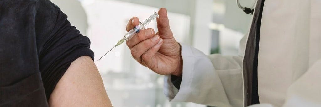 Ein Arzt impft eine Patientin gegen Corona (Symbolbild).