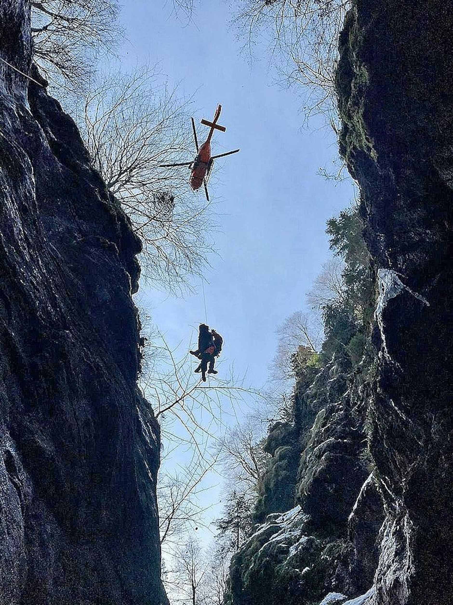 Der verunglückte 18-jährige Wanderer mit einem Retter: Durch einen Berghang werden sie in den Helikopter gezogen.